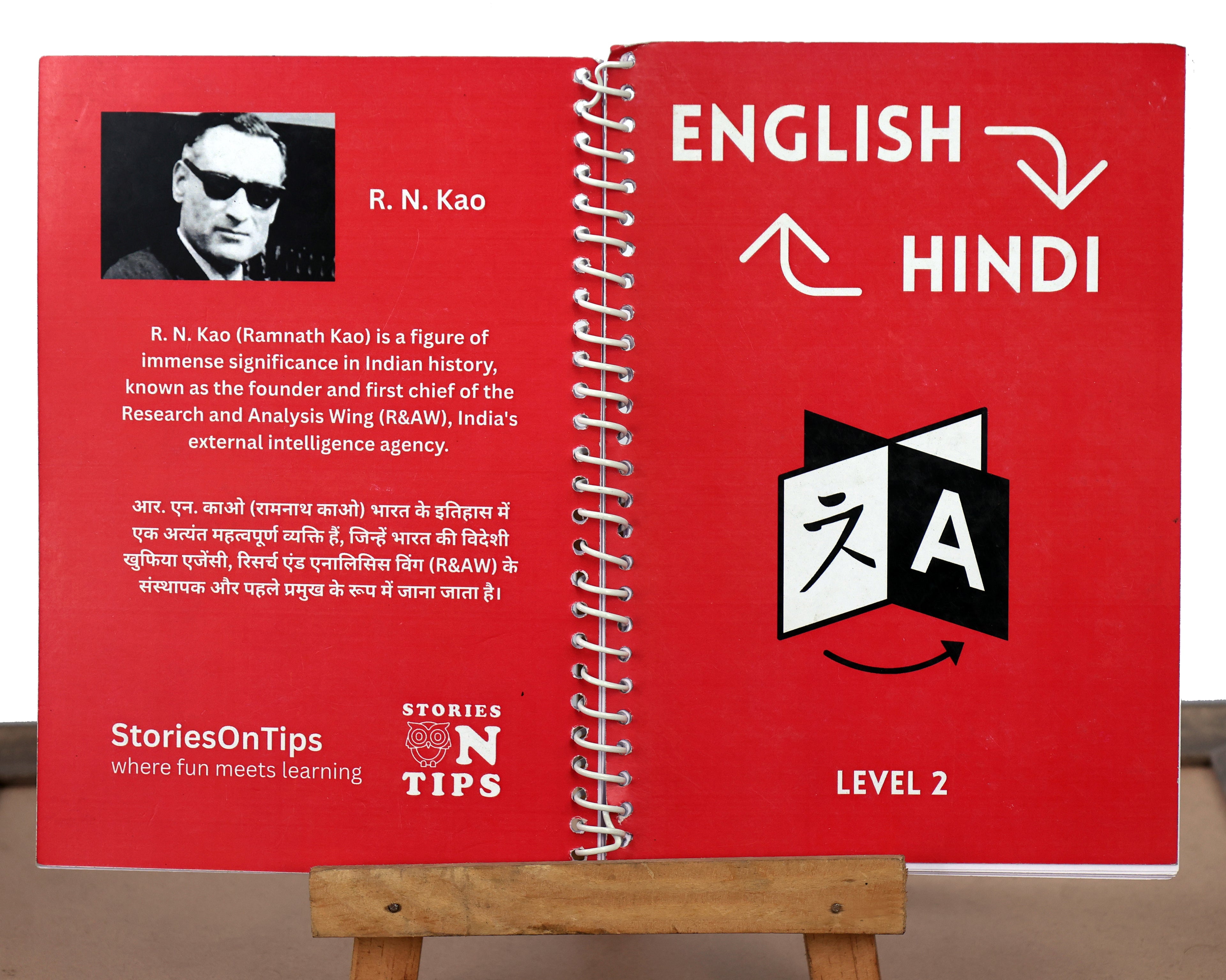 Red bilingual book with English and Hindi text on a stand